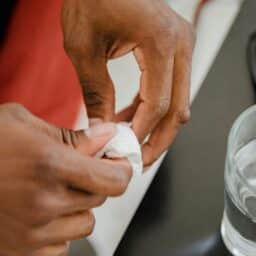 Hands cleaning a hearing aid.
